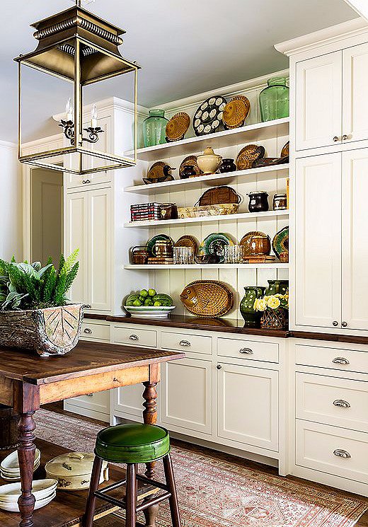 James used majolica pieces and vintage oyster plates to add to the personality of the white kitchen. Neutral greens and worn browns ground the space.
