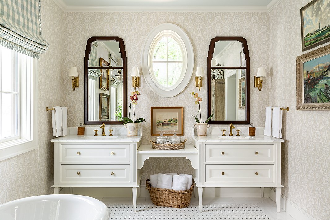 James went light and airy in the main bathroom. Rattan accents, wooden wall mirrors, and art add warmth.
