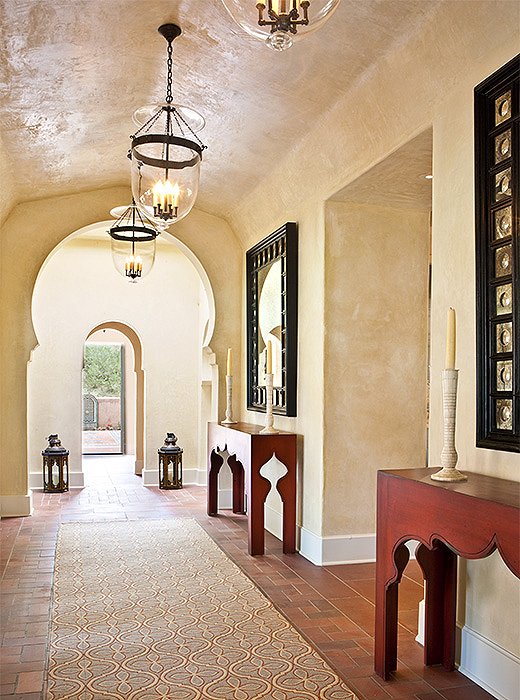 A horseshoe arch and custom consoles featuring a tented motif speak to the home’s Moroccan-inspired design. 

