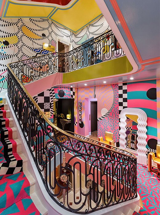 A surreal stairway aptly reflects designer Sasha Bikoff’s creative genius. Nods to the Memphis Group abound with walls covered in zigzags, squiggles, and triangles, while a seemingly endless carpet transports the mind to Alice’s Wonderland.
