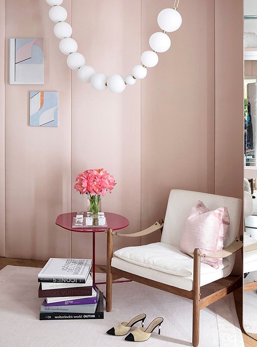 A sculptural light from Semeur d’Étoiles reads like a string of pearls in this dressing room by Marcia Tucker. Casually stacked books on style and a pair of Chanel pumps give guests a clear idea of the woman in Tucker’s design vision. 
