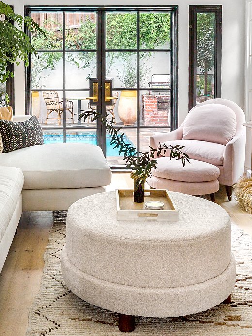 The Cutler Shearling Ottoman serves as a coffee table; just behind are the Lowell Linen Chair and the Lowell Linen Footstool.
