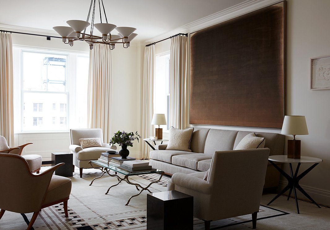 Alyssa used neutral tones in this Upper West Side living room to create a serene ambience. At the same time, the variety of textures and shapes—the curvy metal legs of the coffee table, the Sputnik-like base of the end tables, the sleek rectangular stools next to the soft roll-arm chairs—ensures that the room is anything but dull.
