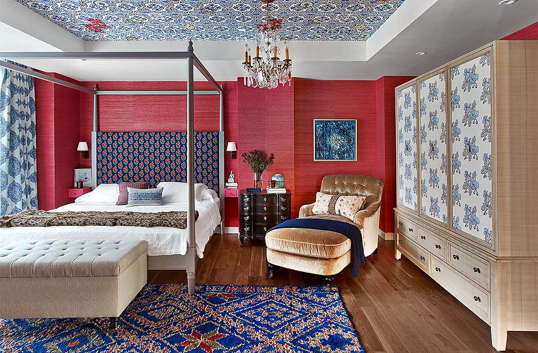 Katie wrapped a bedroom in red grass-cloth paper and dressed it with patterns of varying scale. Hints of royal and navy blues, such as those found in the rug and the headboard, temper the warmth of the walls to create an ideal space for sleep. 
