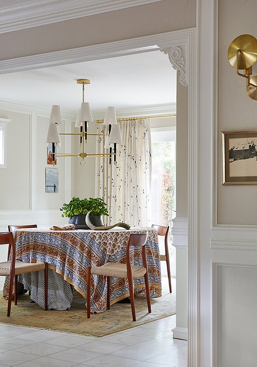 Lynn went neutral with the dining area. A block-printed tablecloth added a pop of pattern to the space. A gold chandelier with linen shades makes a statement over the table.
