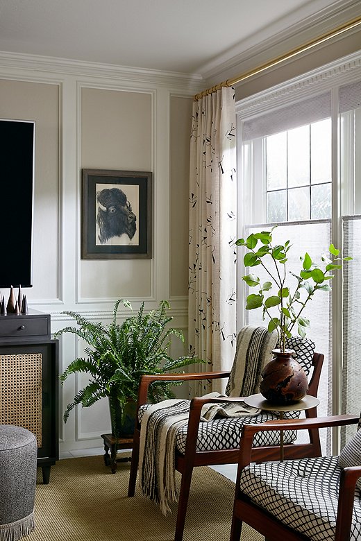 A mix of pattern in subdued colors keeps the family room grounded and visually interesting. A wooden vase and other natural elements bring in some welcome warmth.
