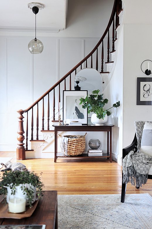 Carli kept as much of the original detailing in the house as possible. The ornate woodwork on the stairs stayed, but she painted it white to help it blend in. She used brown wood furniture throughout the house to ground the space in a traditional sensibility.
