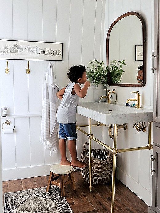 Carli switched a clunky counter for a more historically accurate bathroom sink. She used white shiplap boarding to lighten the space, which has only one small window.
