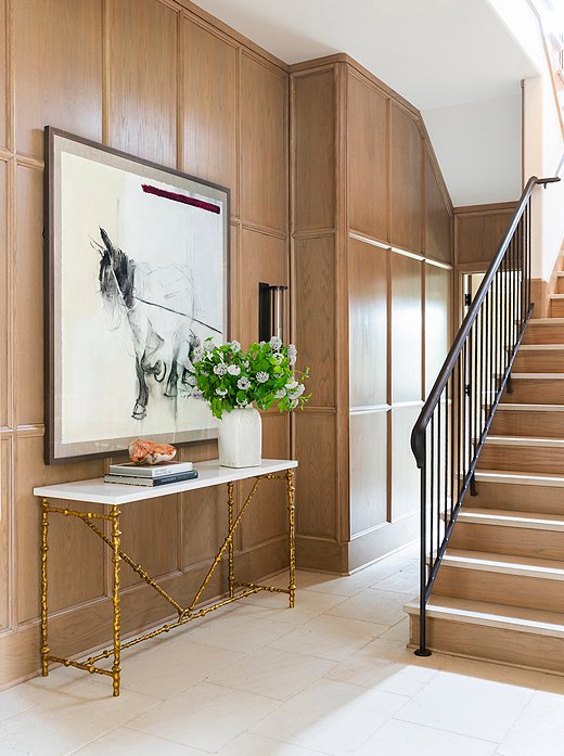 The panel-work in the staircase showcases the raw beauty of the rift-cut oak. The console table’s gilded legs introduce a graphic and geometric moment to the space.
