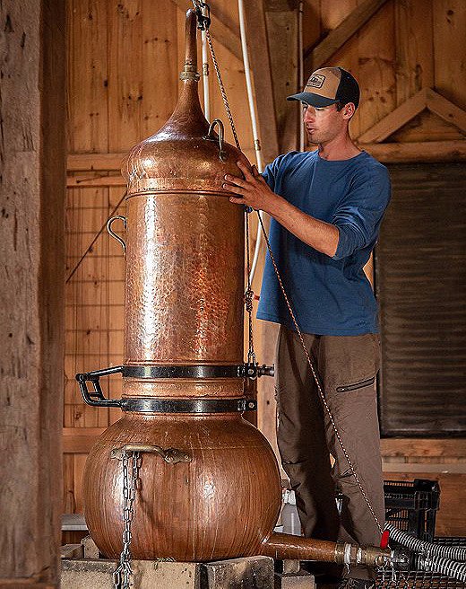 Peter Norman readies the next batch of herbs for distillation atop his copper distillery.
