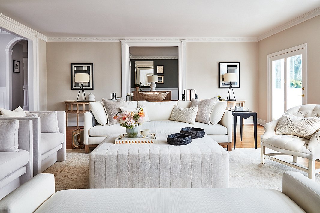 An upholstered ottoman by Tammy Price anchors the living room and is a kid-friendly alternative to a sharp-cornered coffee table. Vintage cable-knit pillows and a pair of woven baskets lend an extra hint of texture to the neutral scheme. Find the sofa here. 
