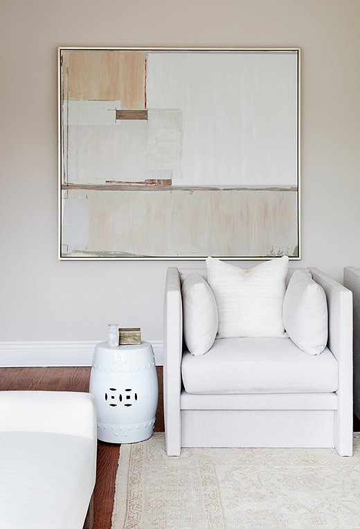 Oversize artwork by Lillian August and a traditional vintage rug add subtle touches of pattern and movement to the space.

