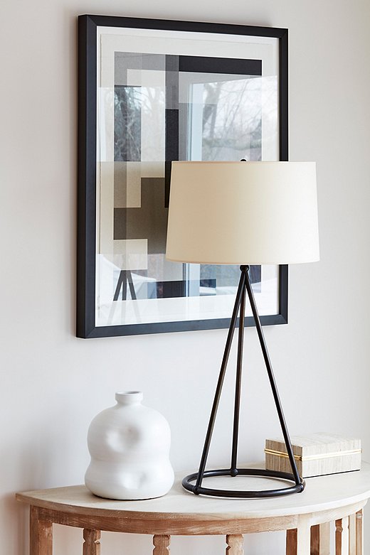 Reclaimed-wood demilunes topped with sculptural lamps and graphic artwork flank one of the living room doorways.
