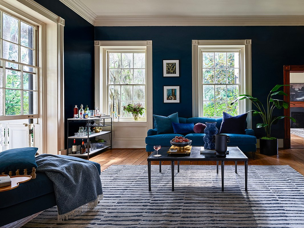The wealth of windows and the pale molding aren’t the only elements keeping this room from feeling overly dark. The white woven through the rug, the light marble shelves of the console table, and even the generous white mats of the framed art help keep the mood luxe rather than lachrymose. Photo by Frank Francis.
