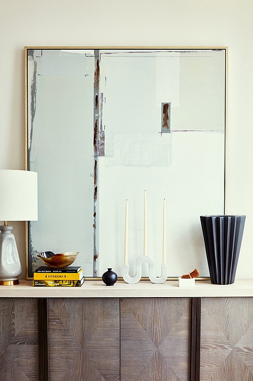 Layering without creating clutter, especially in small spaces, takes a keen eye. Becca opted for one unique candleholder rather than a grouping atop the sideboard. Adding in books, objets, and lamps of various heights is a smart way to entertain the eye. Find the table lamp here.
