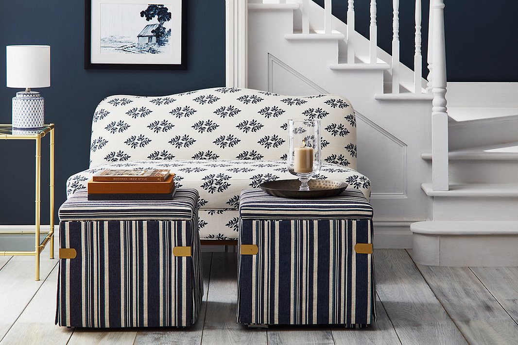 The well-edited palette of Open House makes it easy to mix patterns for a rich layered look. Case in point: the Eleanor camelback settee in indigo sprig, the blue-and-white striped Squires ottomans, and sitting atop the Huntley bar cart, the Archer table lamp.
