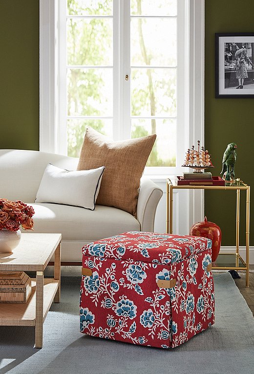 Rubbed-bronze corner tabs elevate the Squires ottoman, seen here in vermilion flora. Bonus: The lid lifts to reveal hidden storage.

