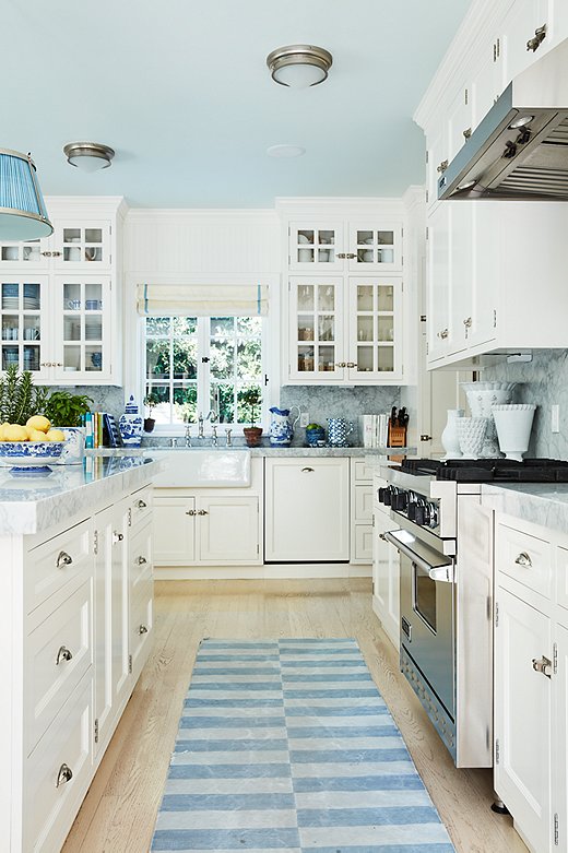 Mark Sikes chose to paint the ceiling of this kitchen a light blue. He carried the color throughout the space with ginger jars, a blue shade on the pendant light, and a blue runner.
