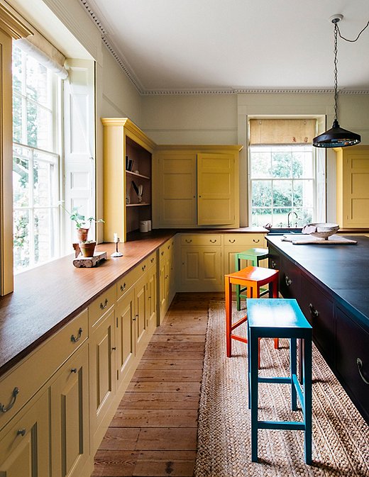 This kitchen takes a next-level approach to color by painting the cabinets in Nicotine and dotting stools painted in Tea Caddy, Medlar Jelly, and Moygashel throughout the room.
