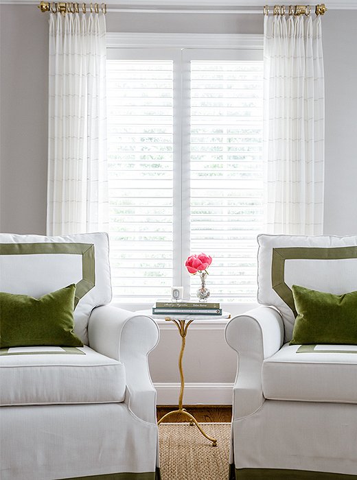 A pair of custom-upholstered armchairs and velvet throw pillows (find similar here) lend a pop of color to the otherwise-neutral master bedroom.
