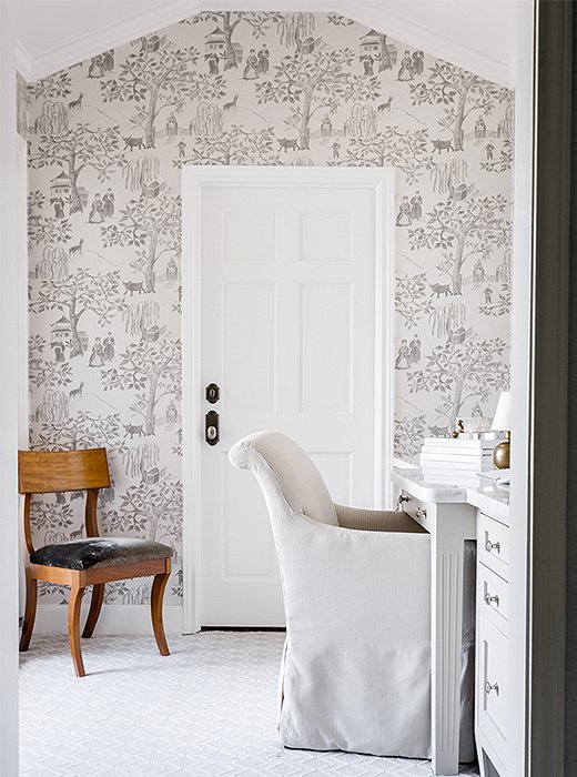 Wallpaper in a gray-and-white pastoral pattern adorns an accent wall in the dressing room.
