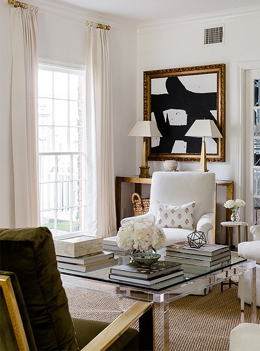 Flanked by a pair of brass lamps, a black-and-white abstract painting speaks to the homeowners’ contemporary taste.
