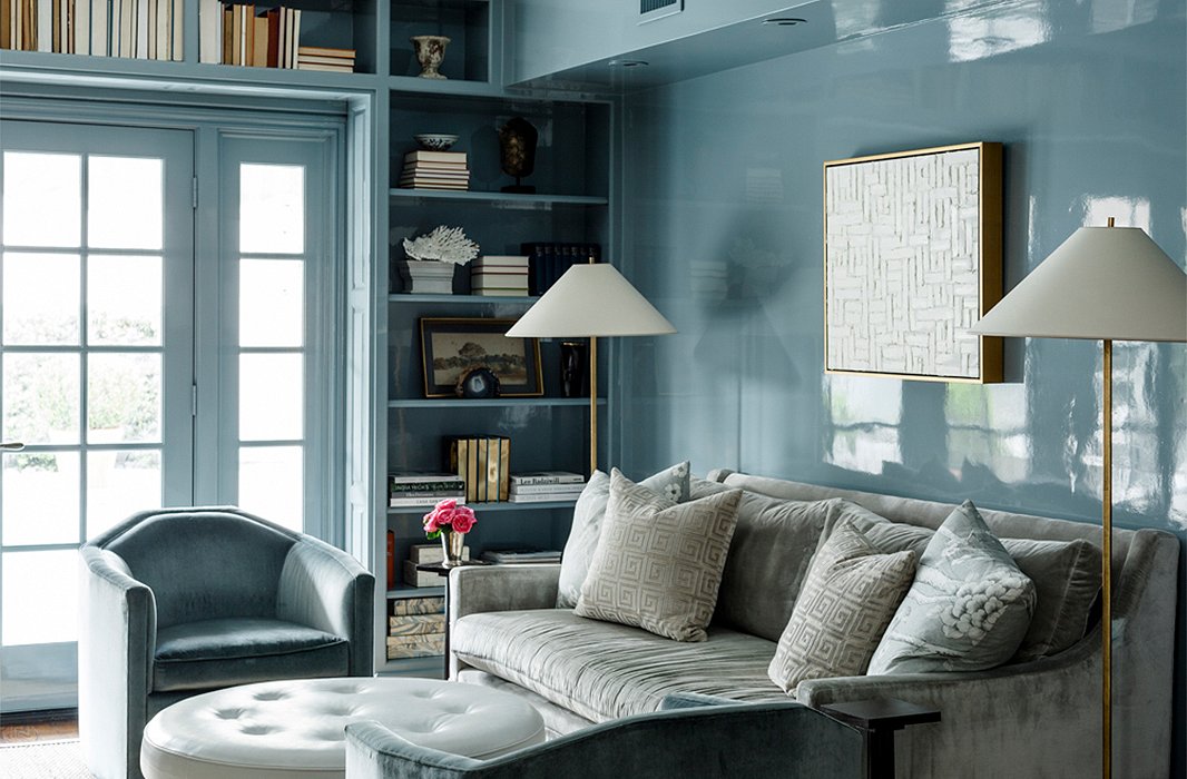 Lacquered in a dreamy blue hue, the home’s cozy library features a round leather ottoman in lieu of a coffee table, artfully arranged shelves, and a gray velvet sofa. Find the chairs here and a similar sofa here.
