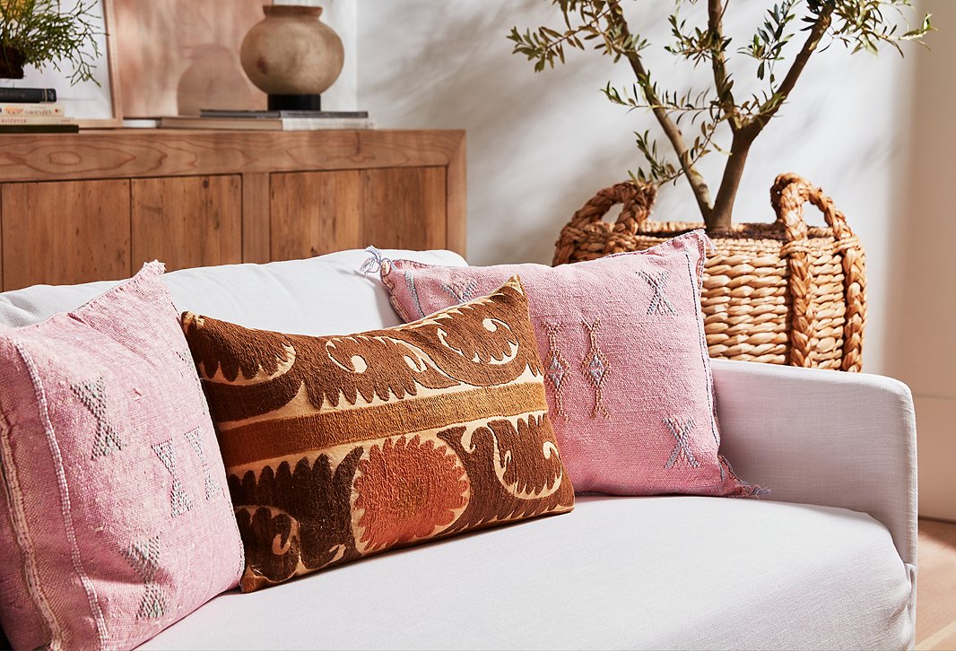 These vintage pillows in pink, brown, and rust brighten up the linen sofa but aren’t so vibrant that they detract from the texture of the woven basket that serves as a planter or the robust figuring of the wood buffet.
