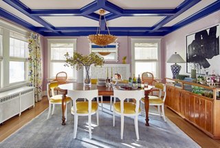 The dining room stuns in an array of color. The ceiling’s trim is Blue by Benjamin Moore, while the rest of the room is draped in complementary lavenders and yellows. The yellow seats are an exact match for the yellow lacquer on the foyer’s ceiling. Find an identical light fixture here.
