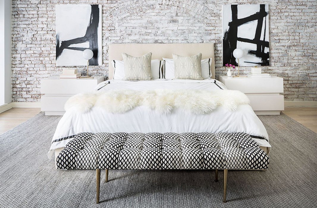 Near-perfect symmetry adds depth and grandeur to the master bedroom. Black-and-white abstracts guide the eye up, while oversize nightstands make the most of the room’s length. 
