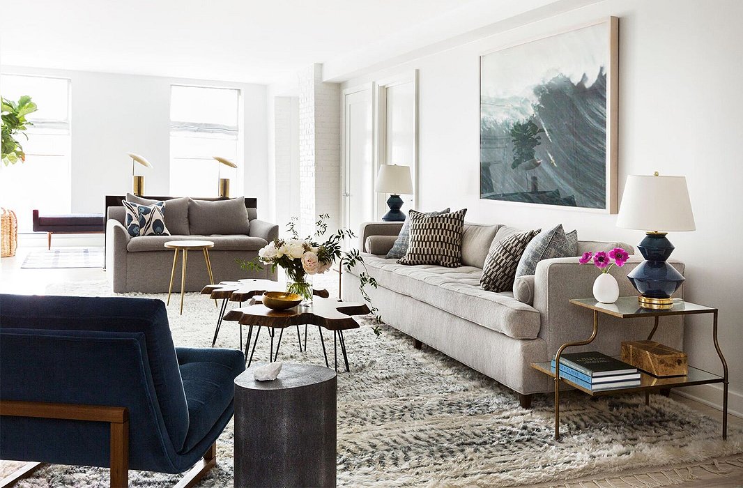 A gray love seat complements a sofa upholstered in a similar hue and a blue midcentury-style chair. Find similar table lamps here.

