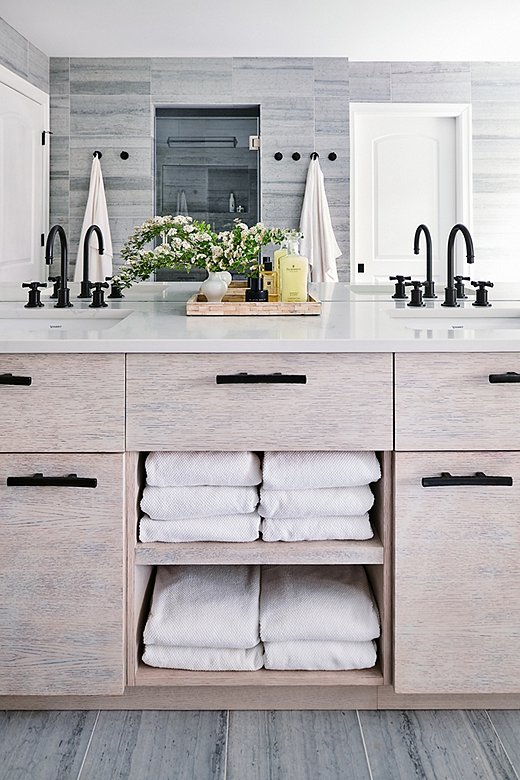 The bathroom’s cool palette and streamlined hardware lean modern. The ingenious touch of farmhouse comes with the rounded-cross sink knobs.
