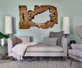 The formal living area uses organic wood art to balance the modern aesthetic of the gray channel-back sofa.
