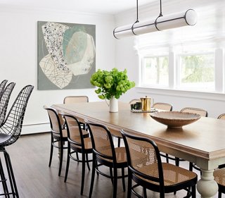 The homeowners have a large immediate family and love to entertain. Tina found a chic farmhouse-style dining table that would seat the entire family for a casual meal. The art at the head of the table brings in the modern aesthetic.
