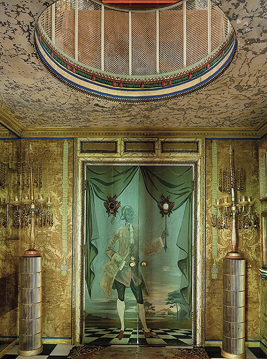 Columns fashioned from air filters flank a door painted by Elizabeth in the entrance hall. 
