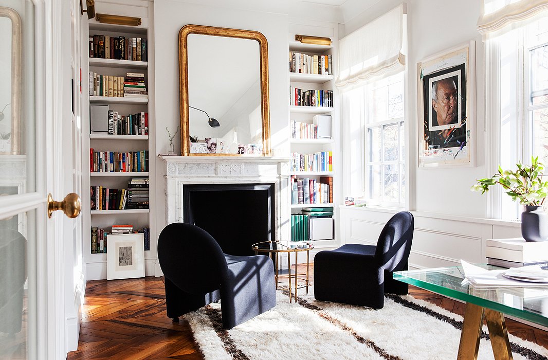 A pair of mod slipper chairs and a Moroccan rug give softness to the light-filled office. The Chuck Close portrait of Jasper Johns at right might be the most colorful piece in the house. The Mason wall mirror is similar to the one resting on her mantel.
