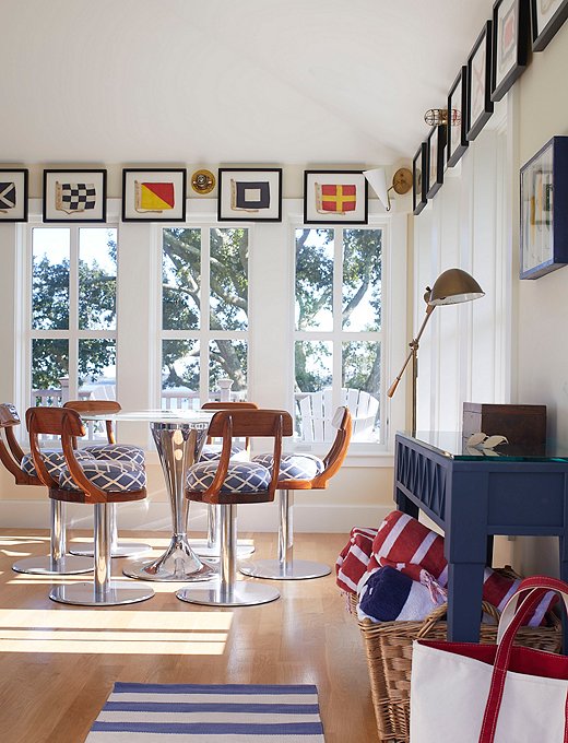 The dining area of the guesthouse features several vintage finds, including framed signal flags and a chrome midcentury table base paired with the same type of swivel chairs that would be bolted to the deck of a performance fishing boat. 
