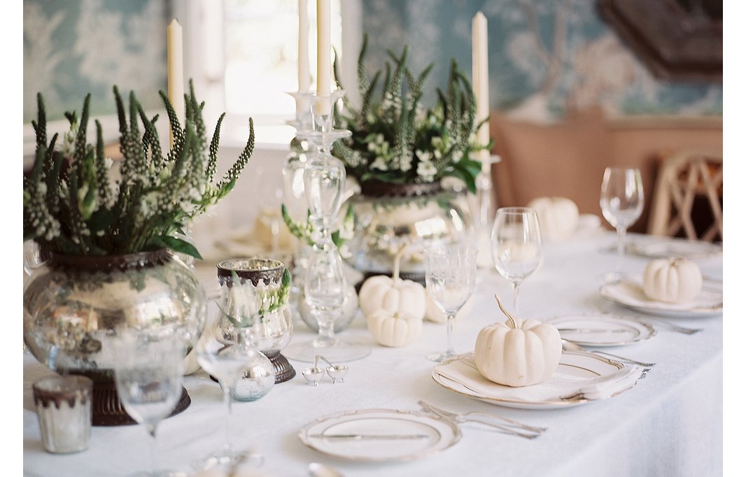 White pumpkins, silvery accents, classic stemware, and gold-rimmed dinnerware make for a decidedly chic and unexpected Thanksgiving look.
