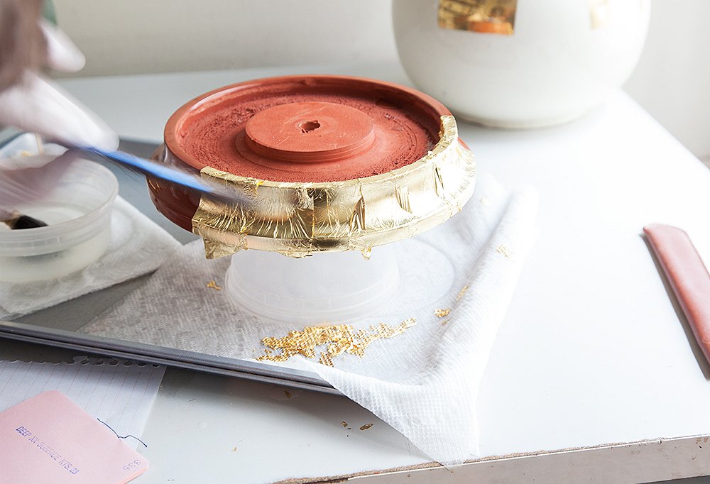 A lamp base gets gilded by hand.
