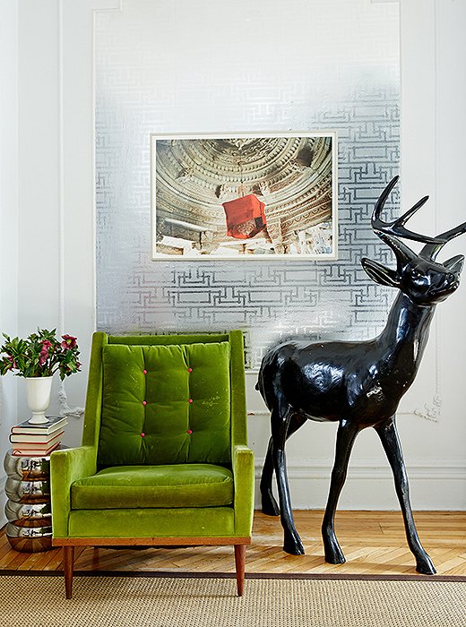 A midcentury chair is covered in a vibrant green velvet. The deer sculpture is a flower-market find that Fawn lacquered in black, which she often uses “to ground a space that has pops of color.” The photograph is by Jonathan Ball.
