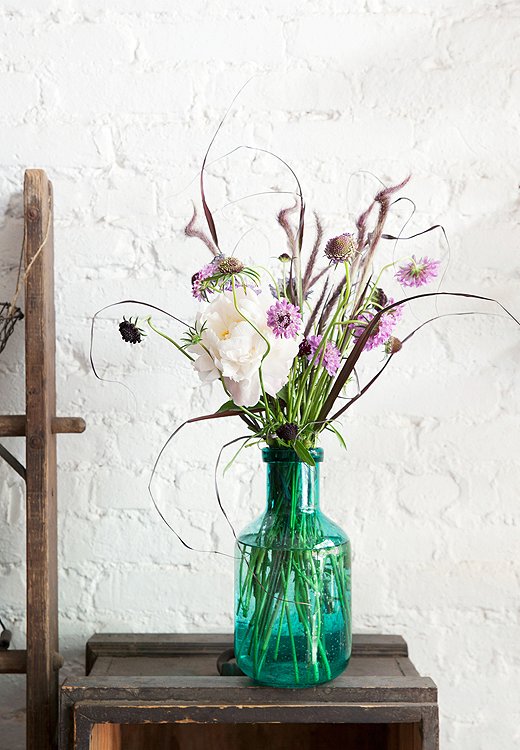 A transparent container, like this blue-grass vase, evokes a casual, seaside mood. Set this bouquet in an entry as a cheerful welcome for guests.
