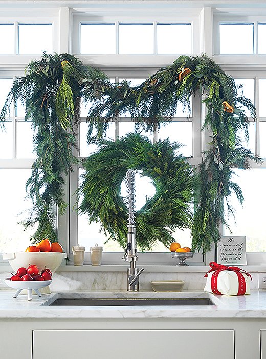 A cedar wreath and swags frame a gorgeous sink; bowls of fruit and a present or two underline the mood.
