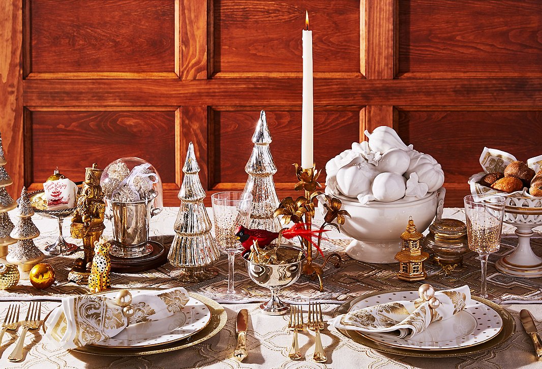 Glass Christmas trees, gold plates and flatware, and a beaded runner make for a decidedly decadent tablescape. 
