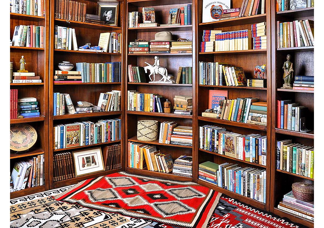 Vintage leather-bound sets, novels, and a collection of baskets and statuettes fill the shelves of this eclectic library.
