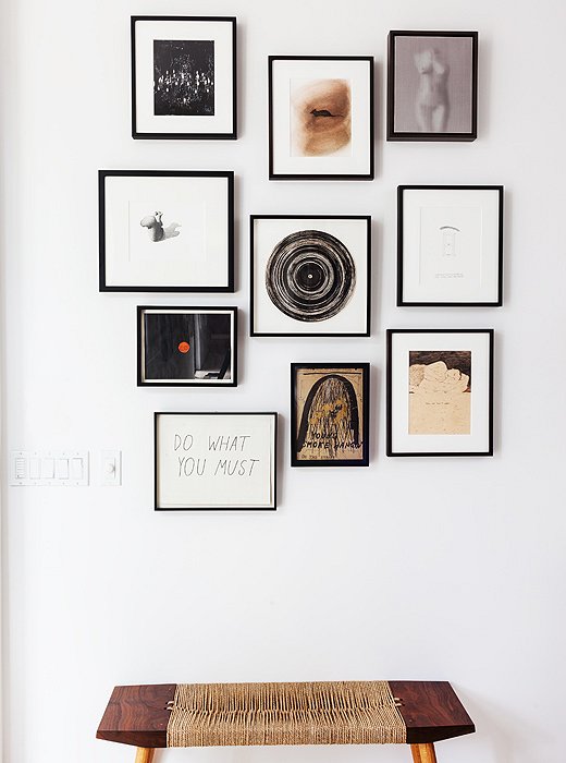 Above a wabi-sabi-style bench, a gallery wall of small-scale art (tied together by the black frames) lies just inside the entry. Works radiate from the central spiral ink drawing by Raymond Pettibon.