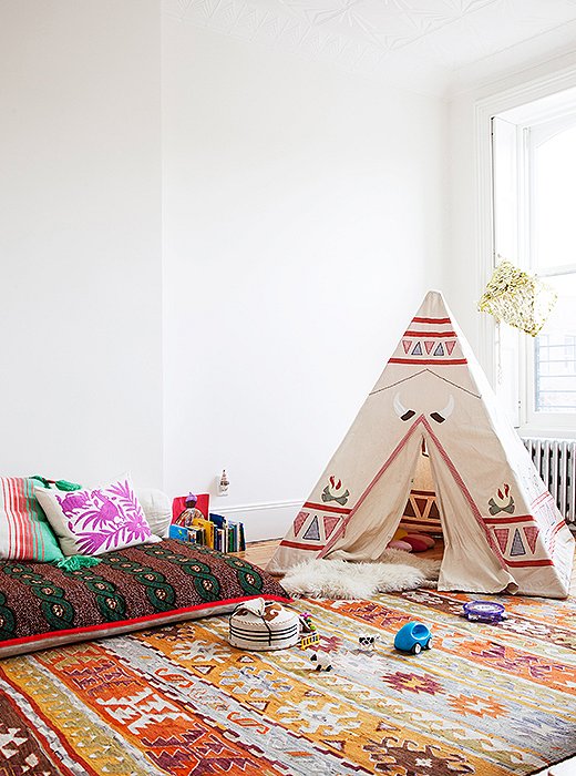 Alongside a mini yurt from Mongolia and an Aztec tepee, an African waxed-cloth floor pillow serves as a sleepover spot and a place to read. The brick-red-and-orange palette is meant to evoke a 1940s vibe.
