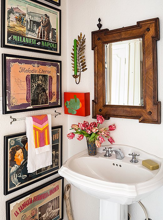 Vintage Italian movie posters line a bathroom wall. The all-white background gives a nook like this an organizing structure, which lets Lulu play around with fun pops of color.
