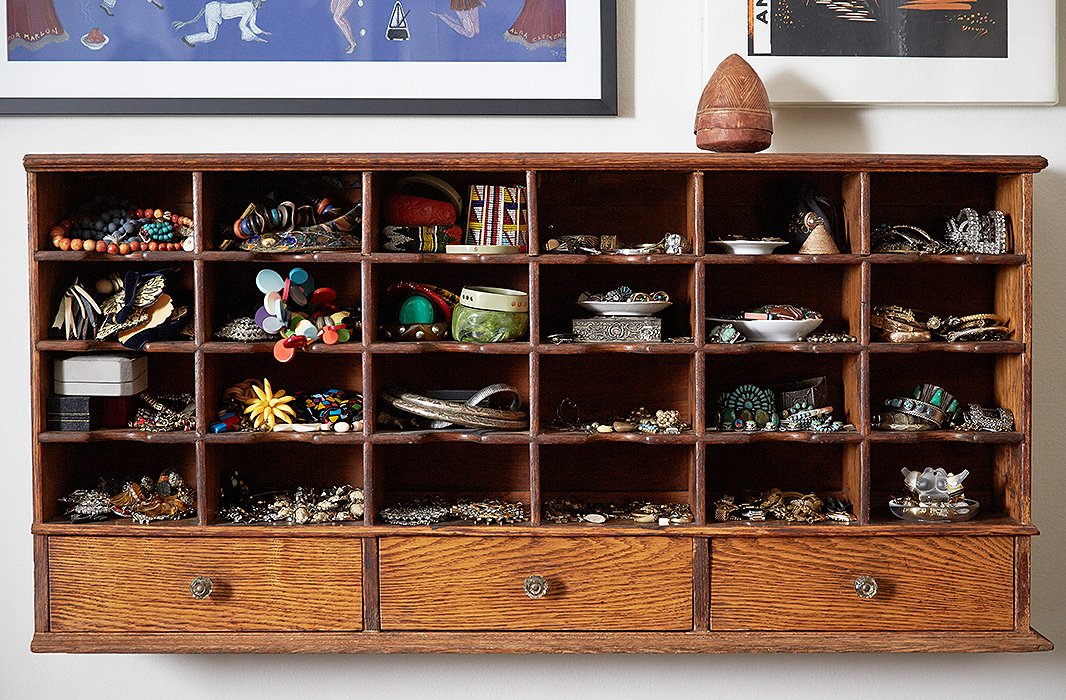 Lisa’s enviable jewelry collection is displayed in plain view on an old wooden shelf with cubbies just the right size for her necklaces and porcelain dishes of rings and bracelets. The shelf is incorporated into the couple’s dining room gallery wall. “It’s my jewelry box,” says Lisa, “and I love having everything easily accessible.”
