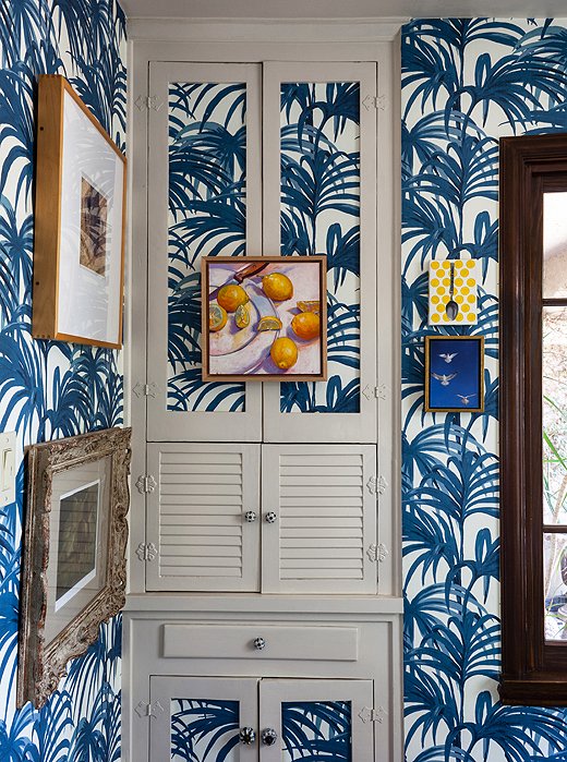 Papering built-in doors visually integrates them into the walls so that they all but disappear. A small oil painting, cleverly hung from the cupboard doorknobs, completes the camouflaged effect and is a cinch to remove.
