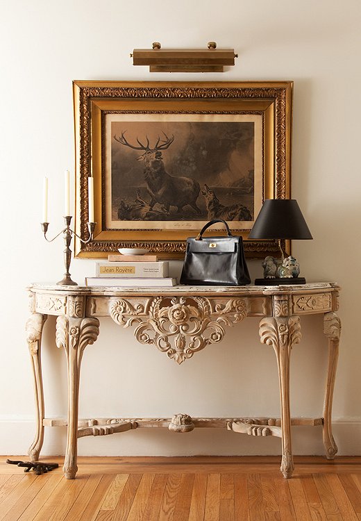 Whether you’re coming or going, an unfinished carved wood table and a grandly framed flea market find create an eye-catching moment in Smith’s entryway.
